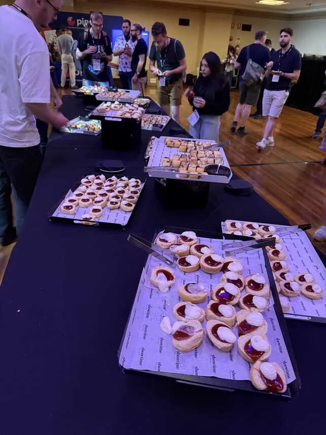 Attendees helping themselves to sausage rolls and scones with jam and cream