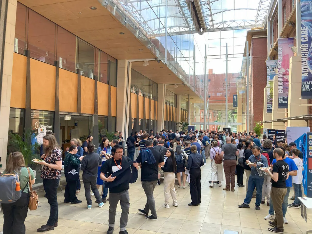 Attendees chatting and eating in the atrium at lunchtime