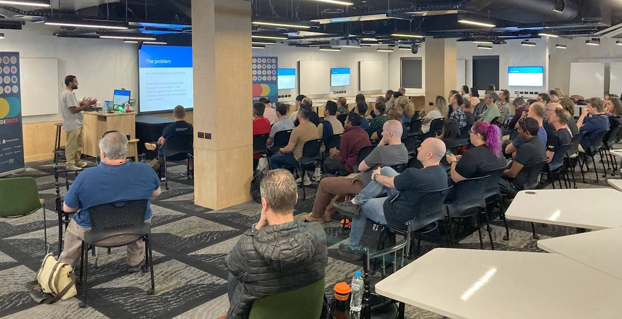 A session in progress with a speaker in front of a large group of seated attendees