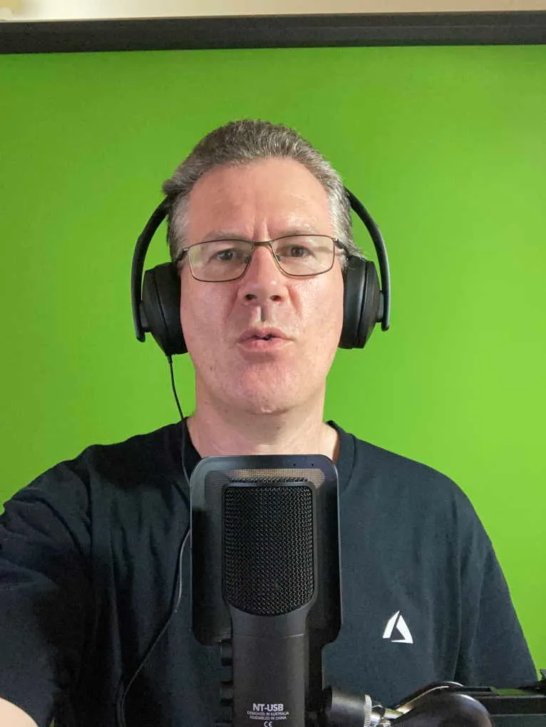 David sitting in front of the screen with a microphone