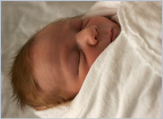 A newborn baby wrapped up and asleep